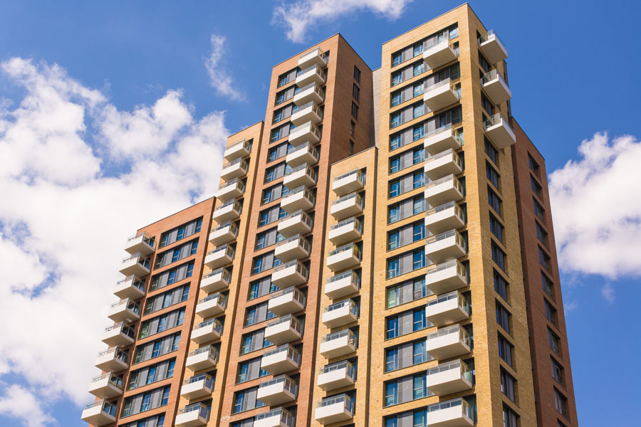 New block of modern apartments with balconies and blue sky in the background