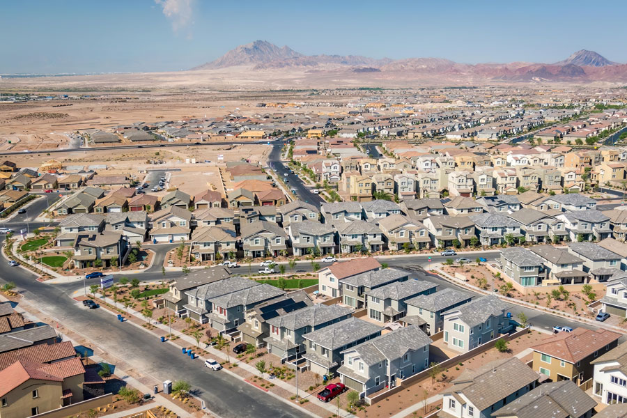 Aerial view captures the sprawling residential area of Henderson, Las Vegas, Nevada, featuring newly built homes with desert mountains in the background on a sunny day