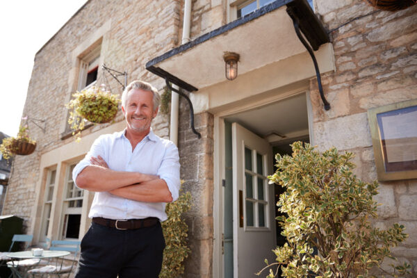 Senior male Landlord stands outside an entrance