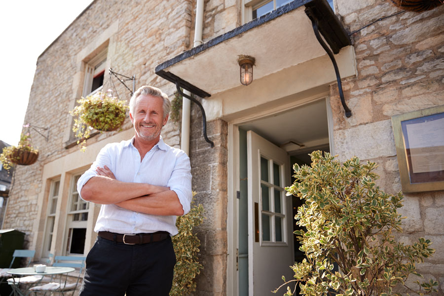 Senior male Landlord stands outside an entrance